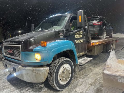 Forest City Roadside flatbed tow truck working at night in a snowstorm in London Ontario