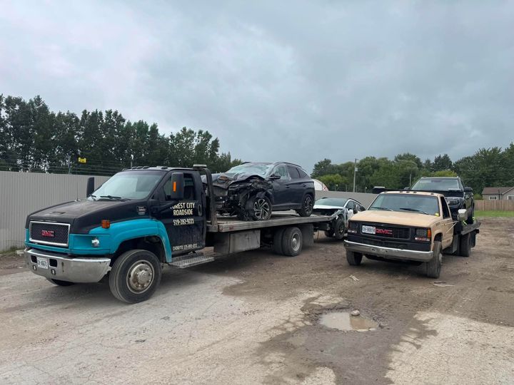 Two Forest City Roadside GMC flatbed tow trucks loaded with vehicles near London Ontario