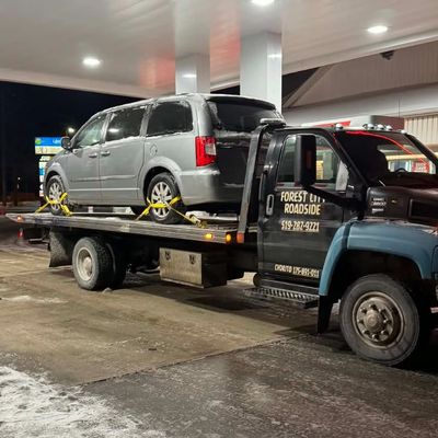 Minivan on a flatbed at a gas station at night