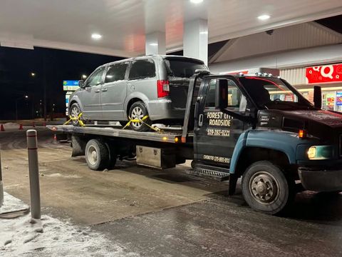 Forest City Roadside tow truck carrying a minivan at a gas station in London Ontario at night